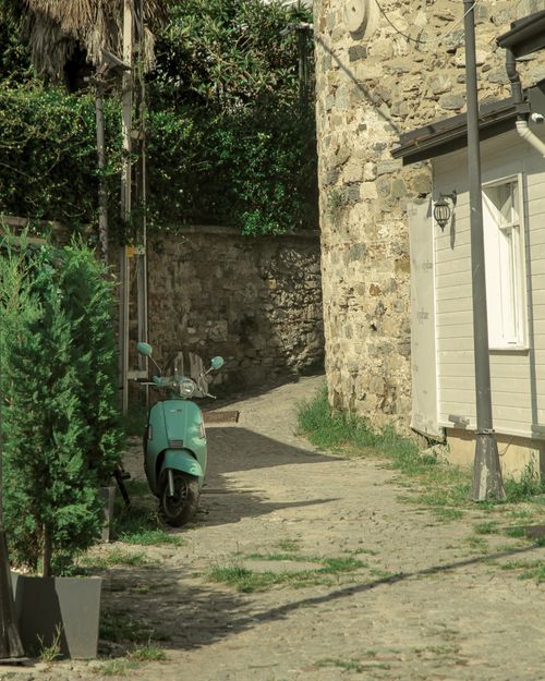 Free A picturesque cobblestone alley with a vintage motorbike parked beside rustic stone buildings. Stock Photo