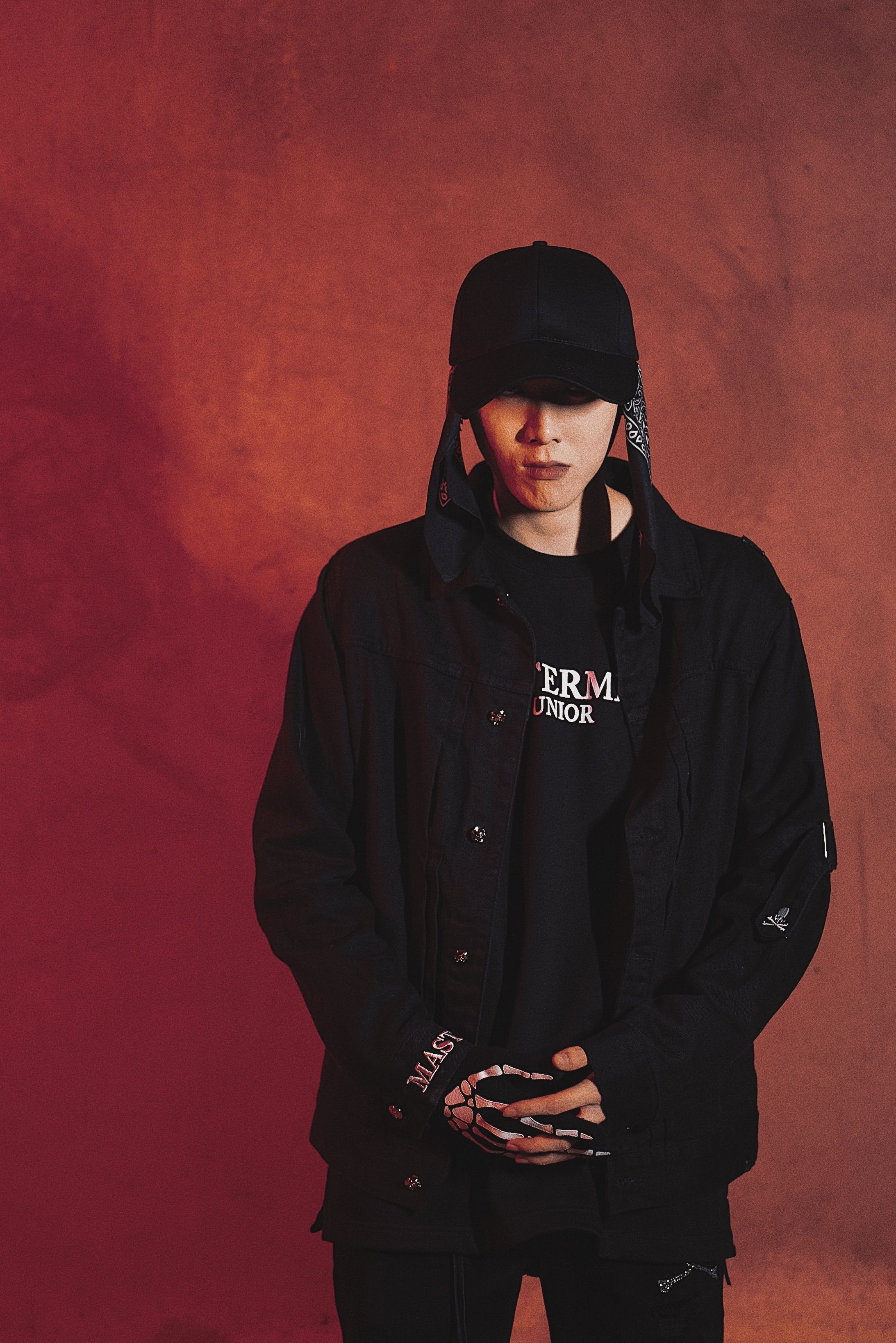 Stylish man in black attire poses against a dramatic red background.
