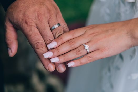 A couple's hands showcasing their engagement rings in a romantic close-up setting.
