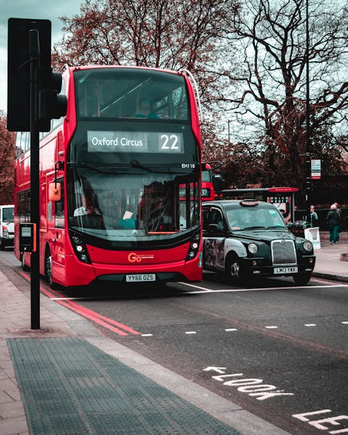 免费 沥青路上黑色出租车旁边的红色双层巴士 素材图片