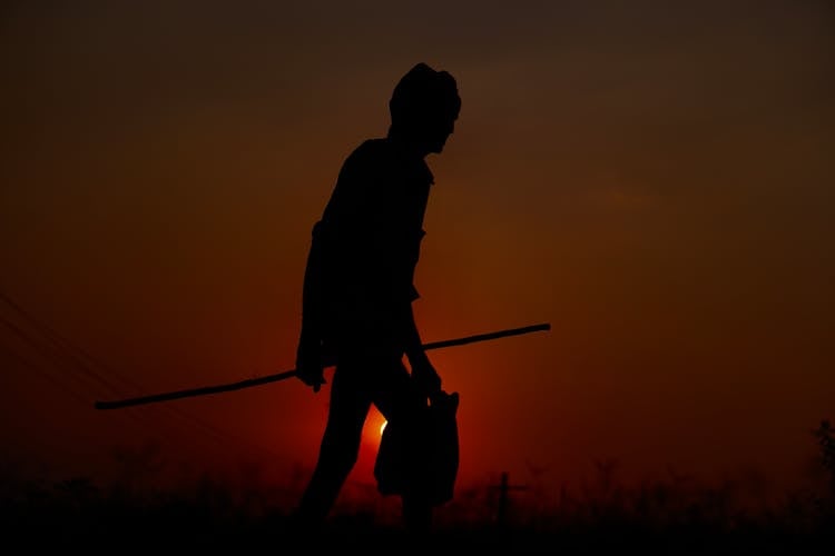 A Man Holding A Stick And A Bag