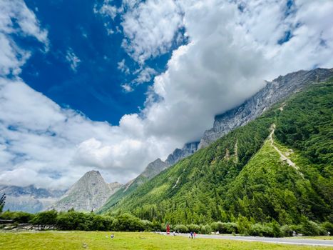 Scenic view of lush green mountains under a vibrant blue sky with white clouds.