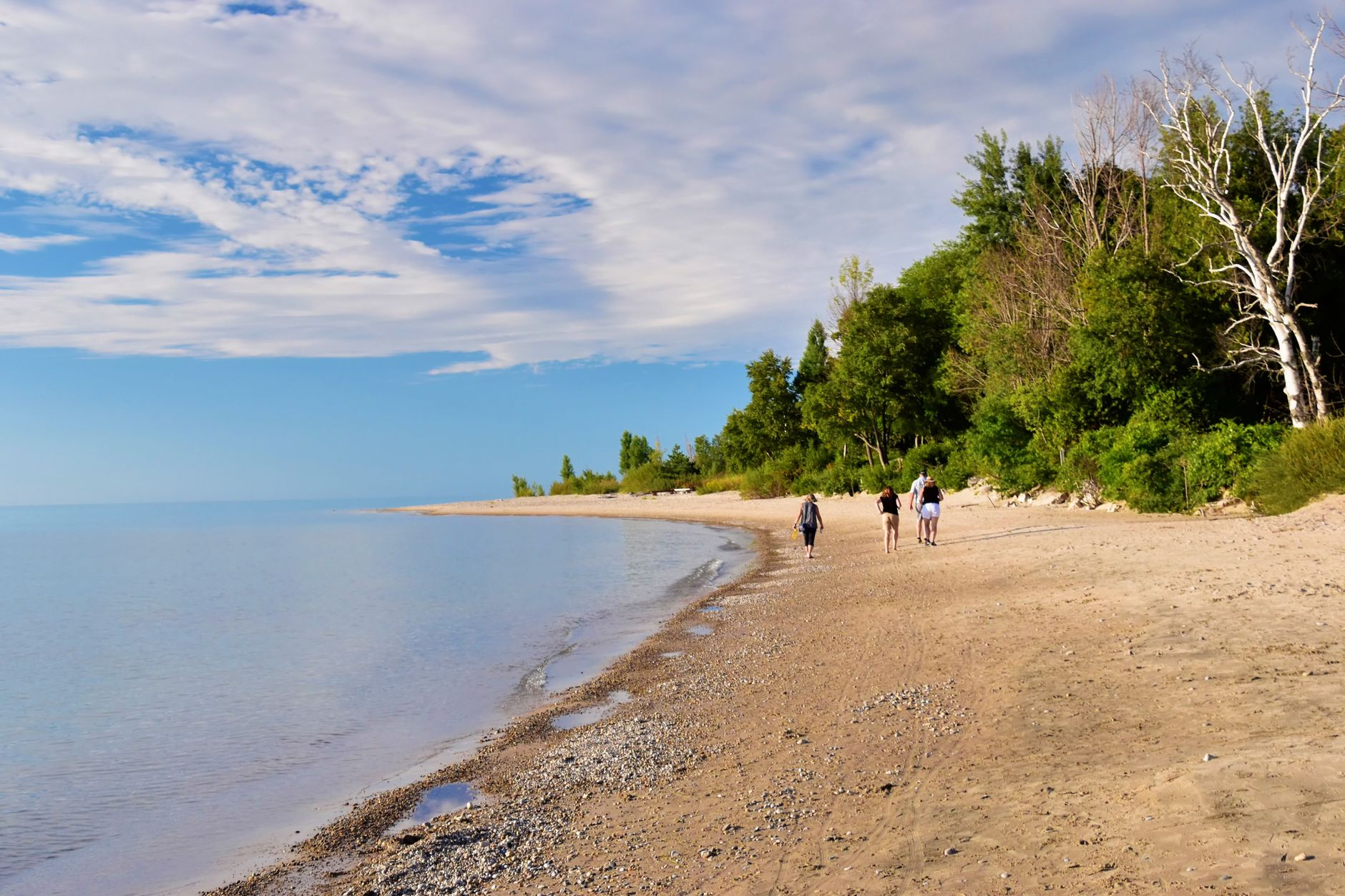 A serene day at the beach in Kincardine, Ontario, with people enjoying a walk by the water.