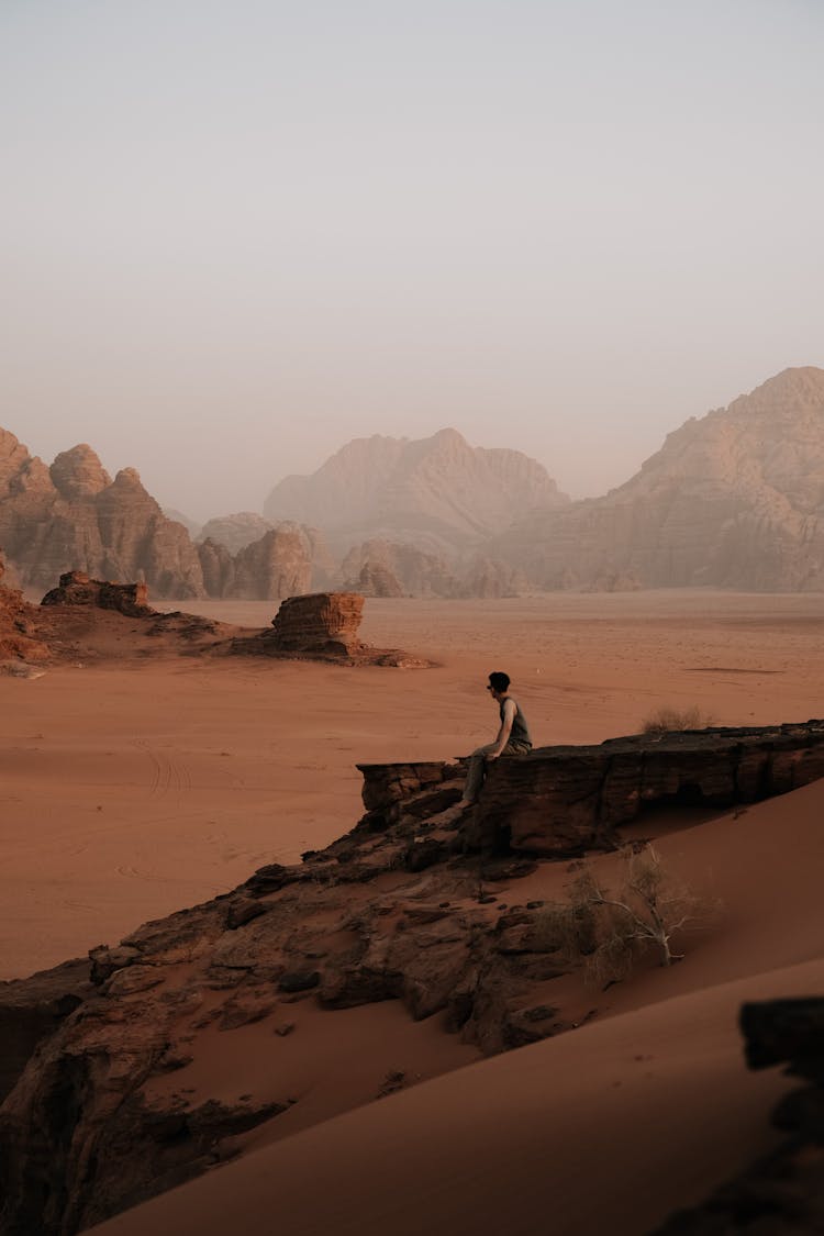 Man Sitting On A Rock In The Wadi Rum Valley In Jordan 