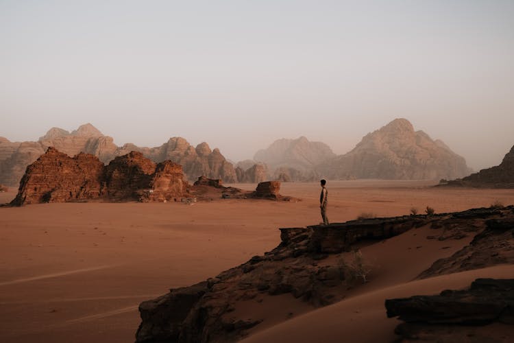 Man Sitting On A Rock In The Wadi Rum Valley In Jordan 