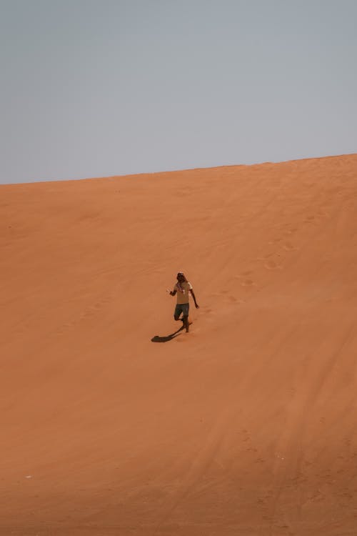 A Person Walking Down Sand Dune
