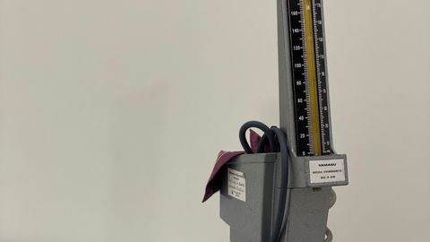 Close-up of an analogue sphygmomanometer against a blank wall in a clinic.