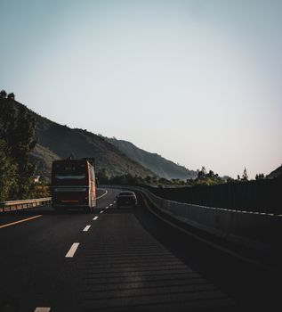 A scenic highway in Murree, Pakistan, featuring a bus and car traveling under a clear sky.