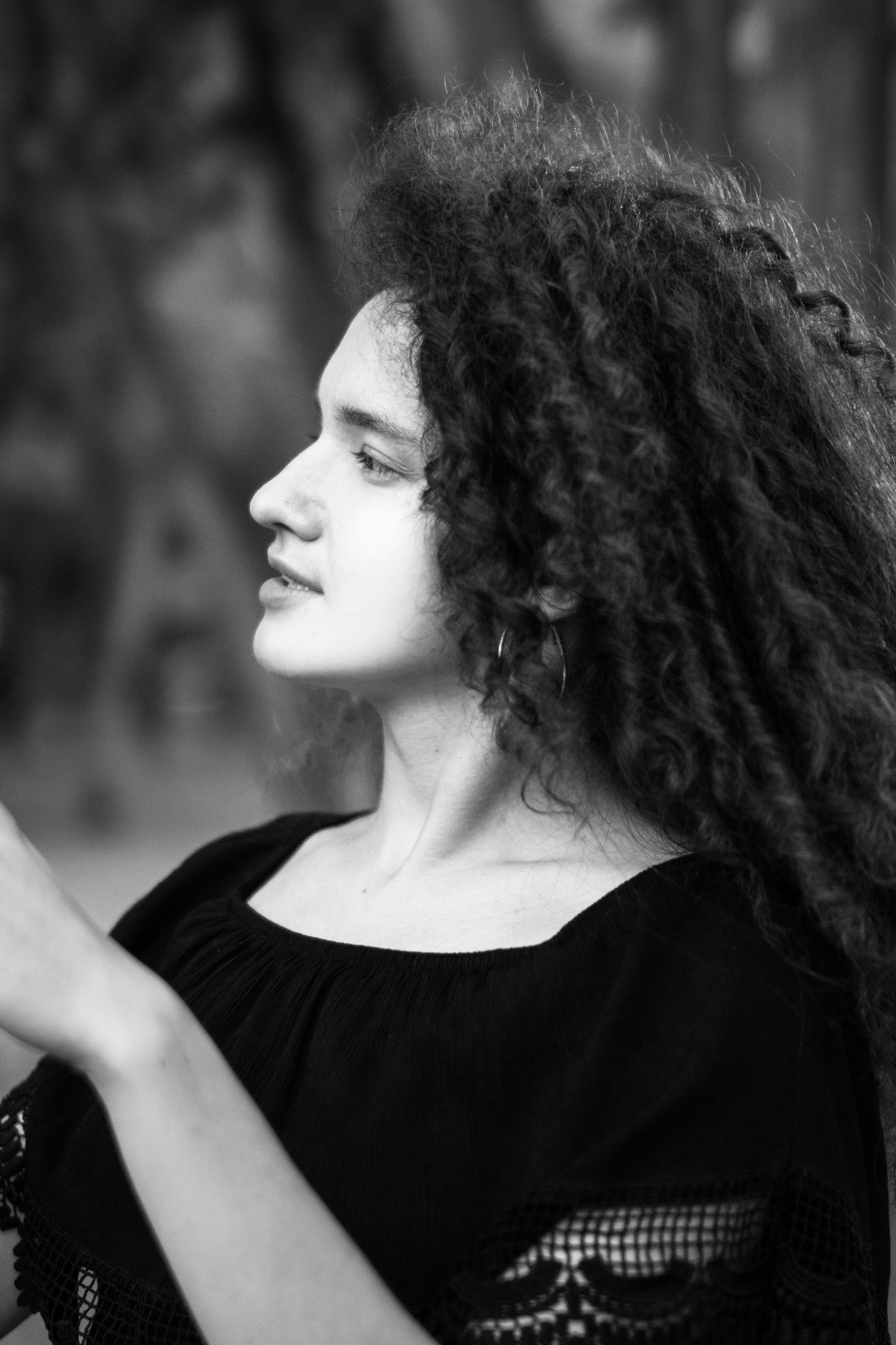 Elegant black and white side profile portrait of a young woman with curly hair.