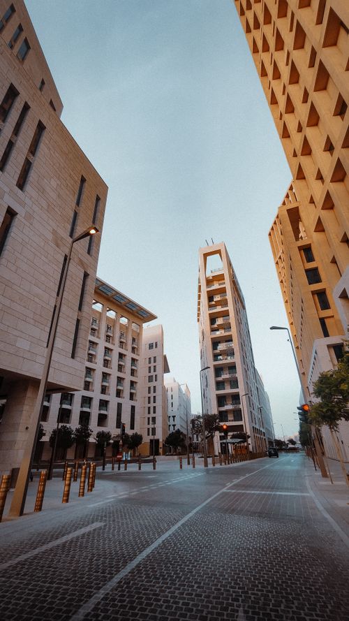 Free A captivating view of sleek, modern buildings forming a canyon-like street scene under a serene evening sky. Stock Photo