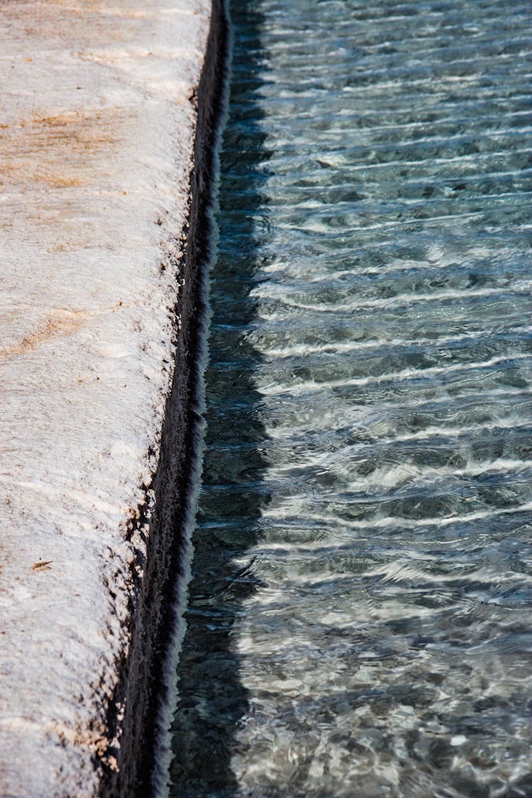 High Angle Shot Of Seawater Crashing On A Concrete Barrier 