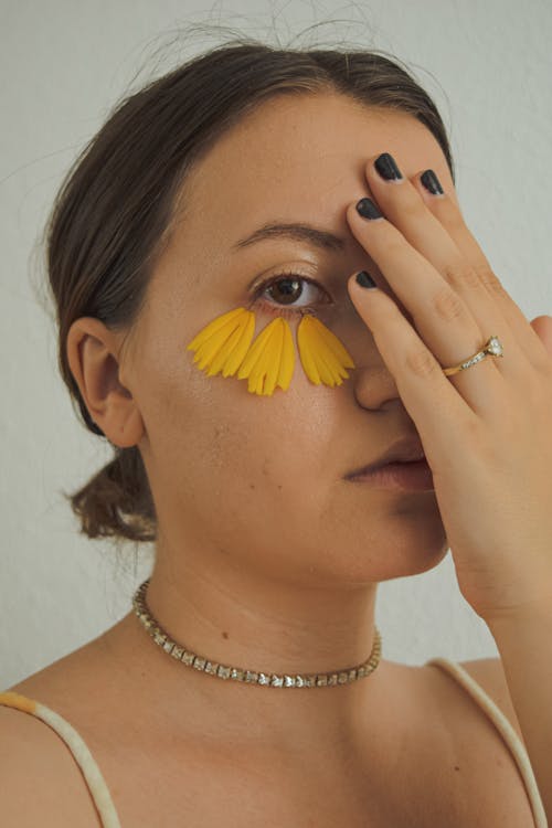 Free Woman in Gold Necklace Covering Her Face With Yellow Flower Stock Photo
