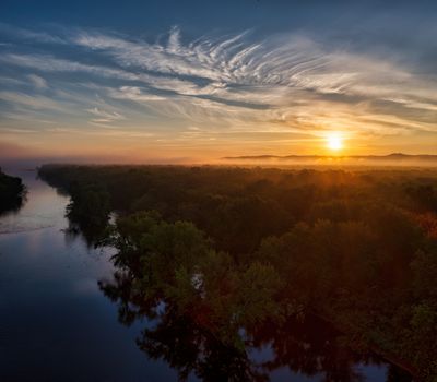 Dramatic aerial view of a sunset over a river and forest in Trevino, WI, USA.