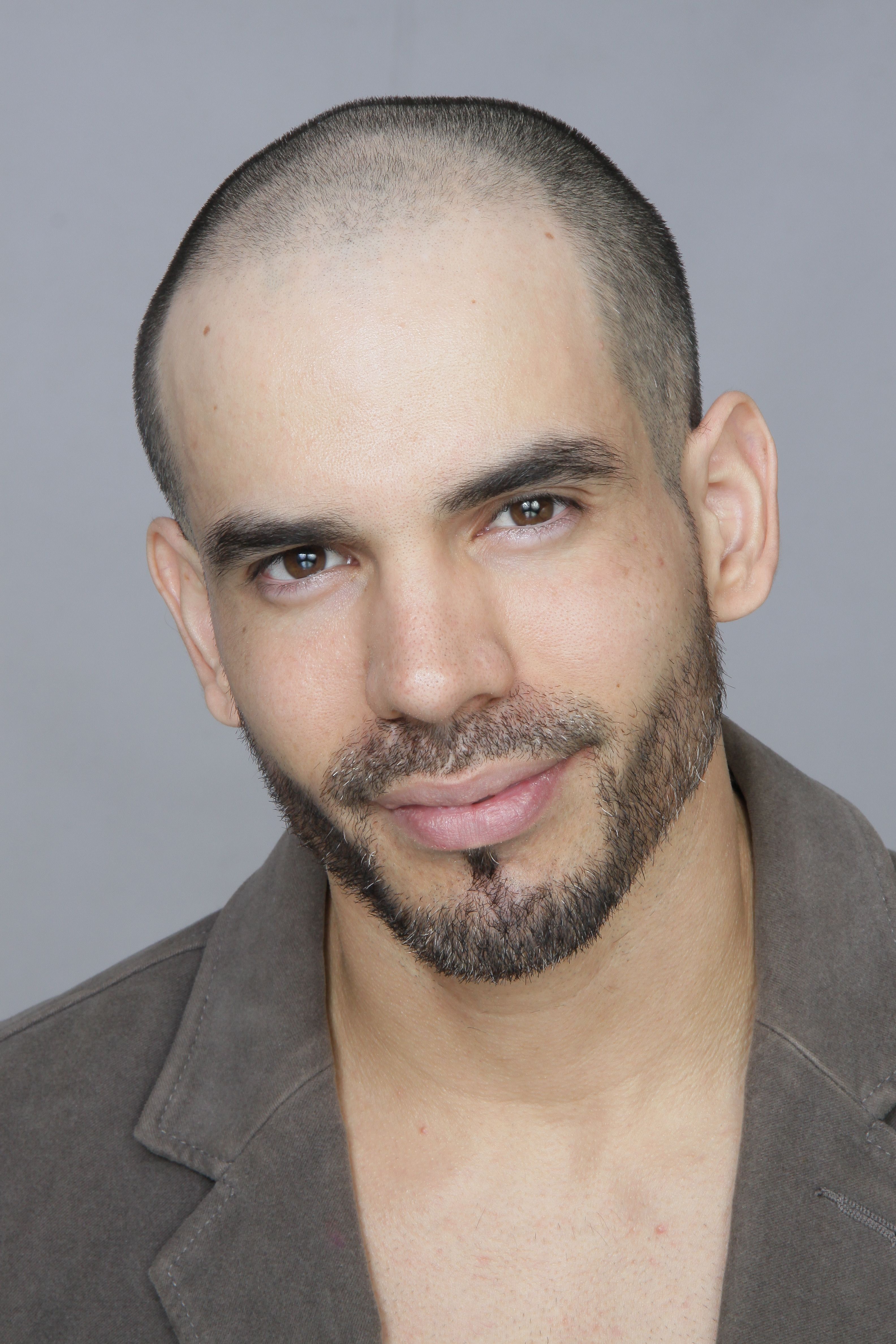 Close-up portrait of a bald man with facial hair, exuding confidence and style.