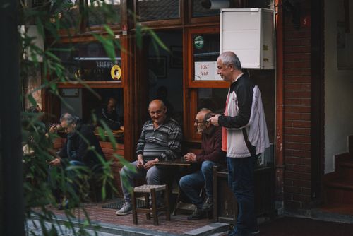 Free Three elderly males enjoying a conversation outside a cozy cafe. Stock Photo