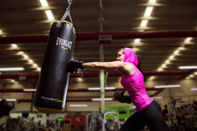 Active Woman In Pink Fitwear Punching A Punching Bag 