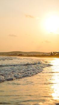 Enjoy the serene beach with gentle waves at sunset during summer. Perfect for a relaxing getaway.