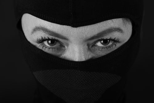Free Close-up of a person's intense eyes staring through a black mask in black and white. Stock Photo