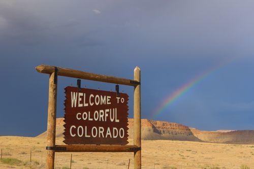 Free Iconic Colorado welcome sign with a rainbow and desert backdrop. Stock Photo