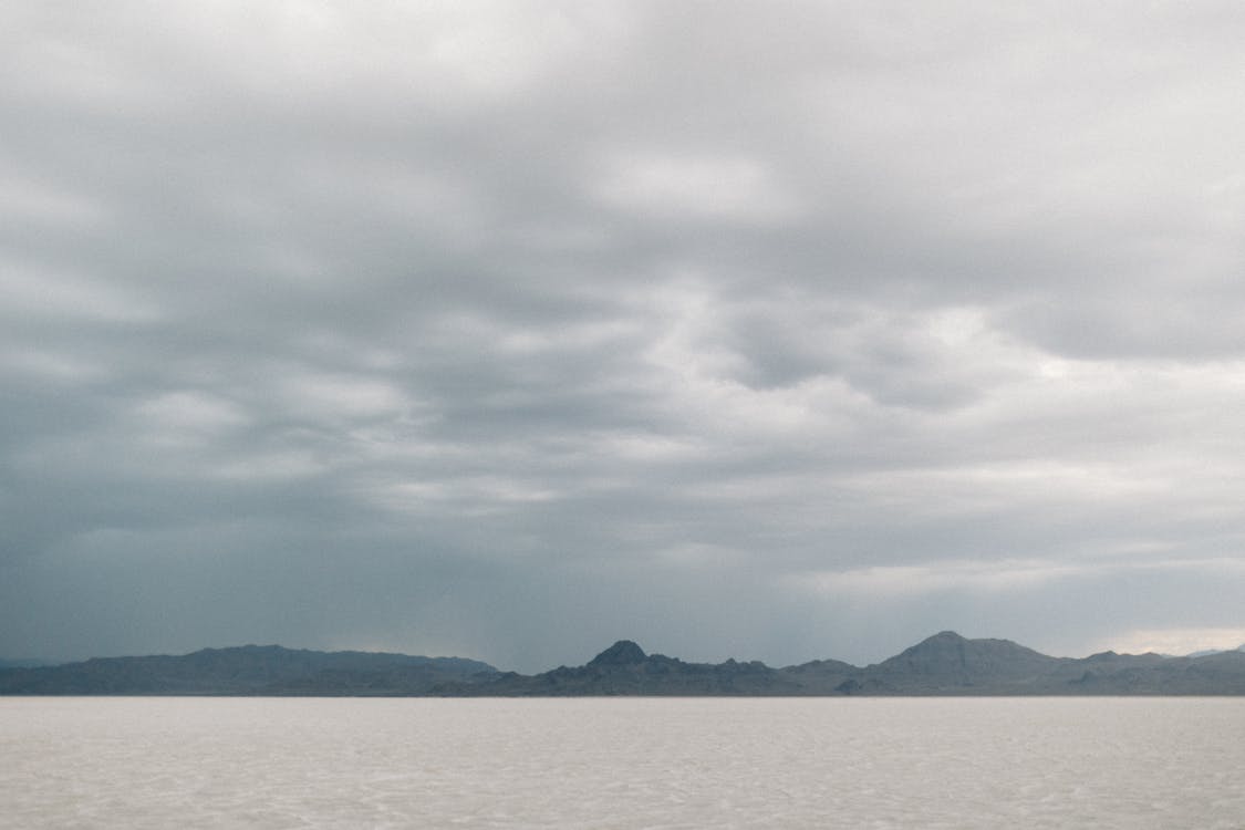 Hill Ranges near Lake under Cloudy Sky 