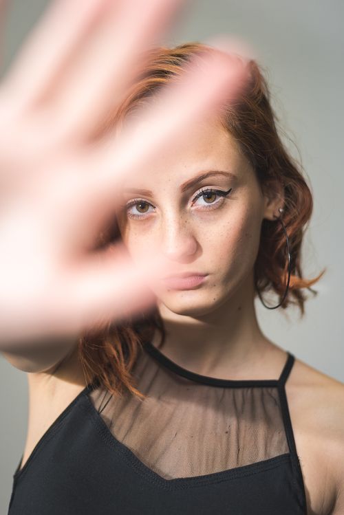 Free Close-up portrait of a young woman with an outstretched hand in focus, expressing individuality. Stock Photo