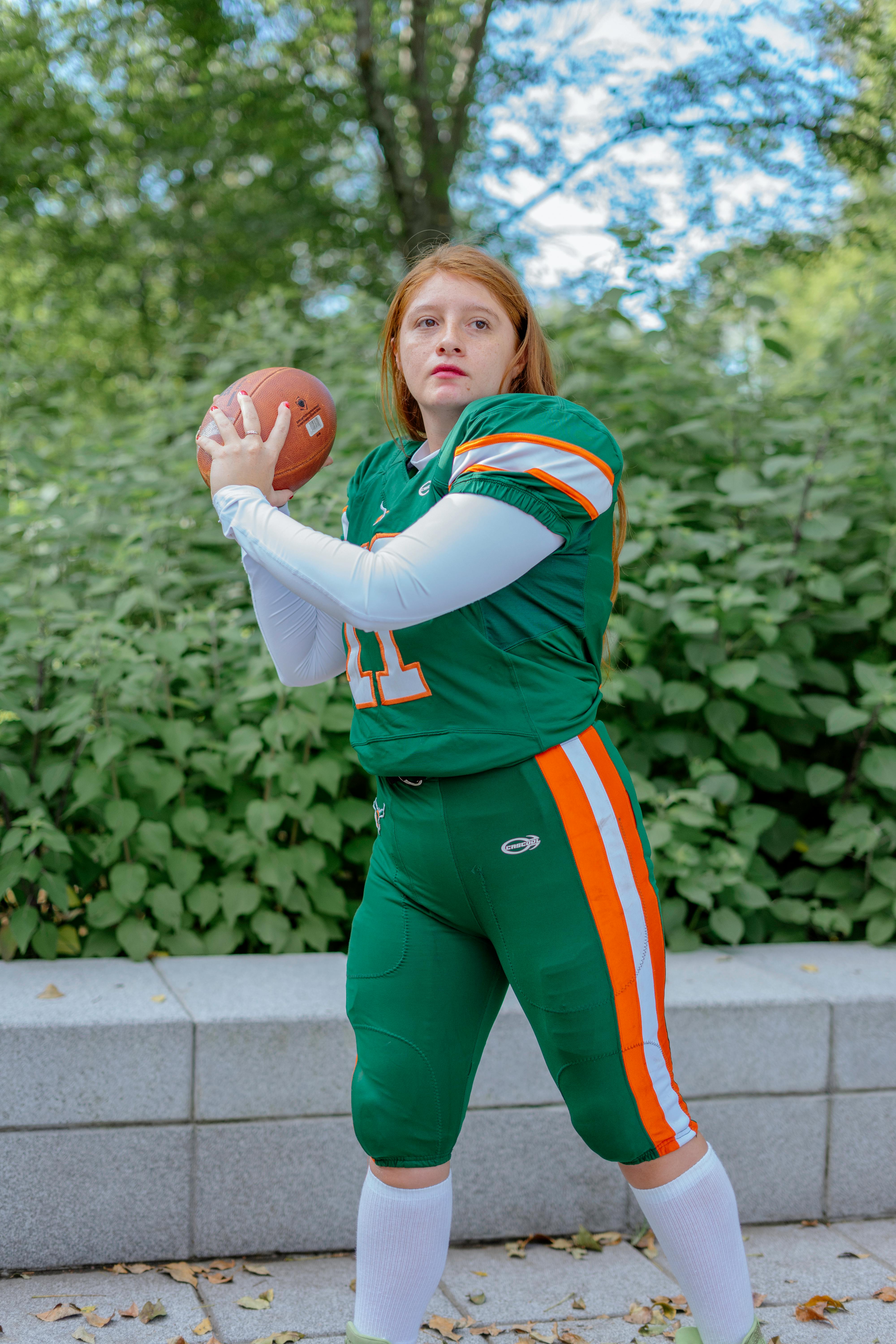 Redhead Girl Holding a Ball and Wearing an American Football Game