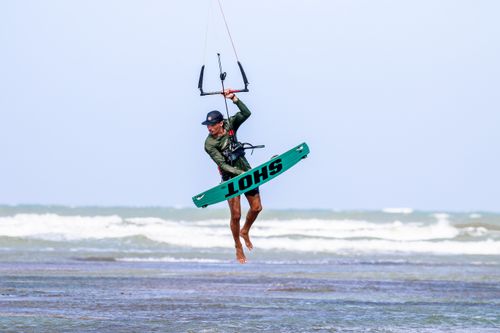 Free Kitesurfer catching air above the waves in Adicora, Venezuela, showcasing watersport excitement. Stock Photo