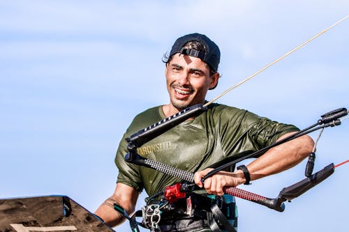 A Man in Green Shirt Kitesurfing on the Beach