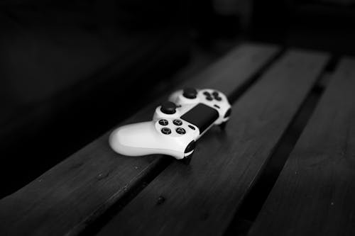 Bezpłatne Biały Kontroler Sony Dualshock 4 Na Powierzchni Z Czarnego Drewna Zdjęcie z galerii