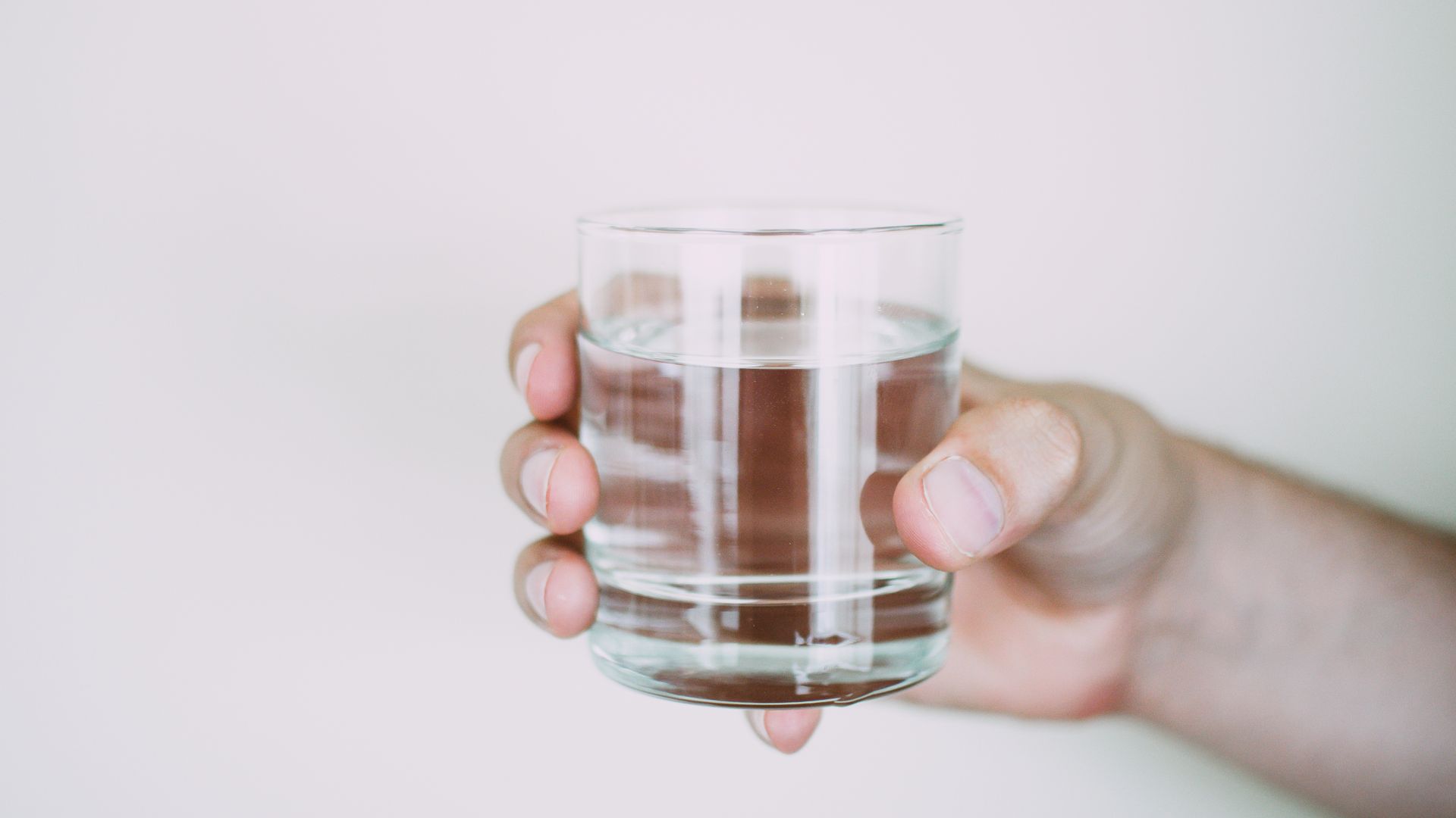 Modafinil Water Intake Tips: Maximize Your Hydration A close-up shot of a hand holding a clear glass of water, symbolizing refreshment — modafinil water intake tips