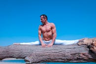 一名男子在蓝天下做瑜伽，于户外展示其灵活性与健身能力