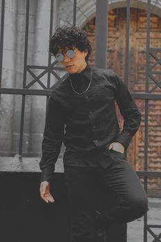 Fashionable man in black outfit by a metal gate in Mexico City.