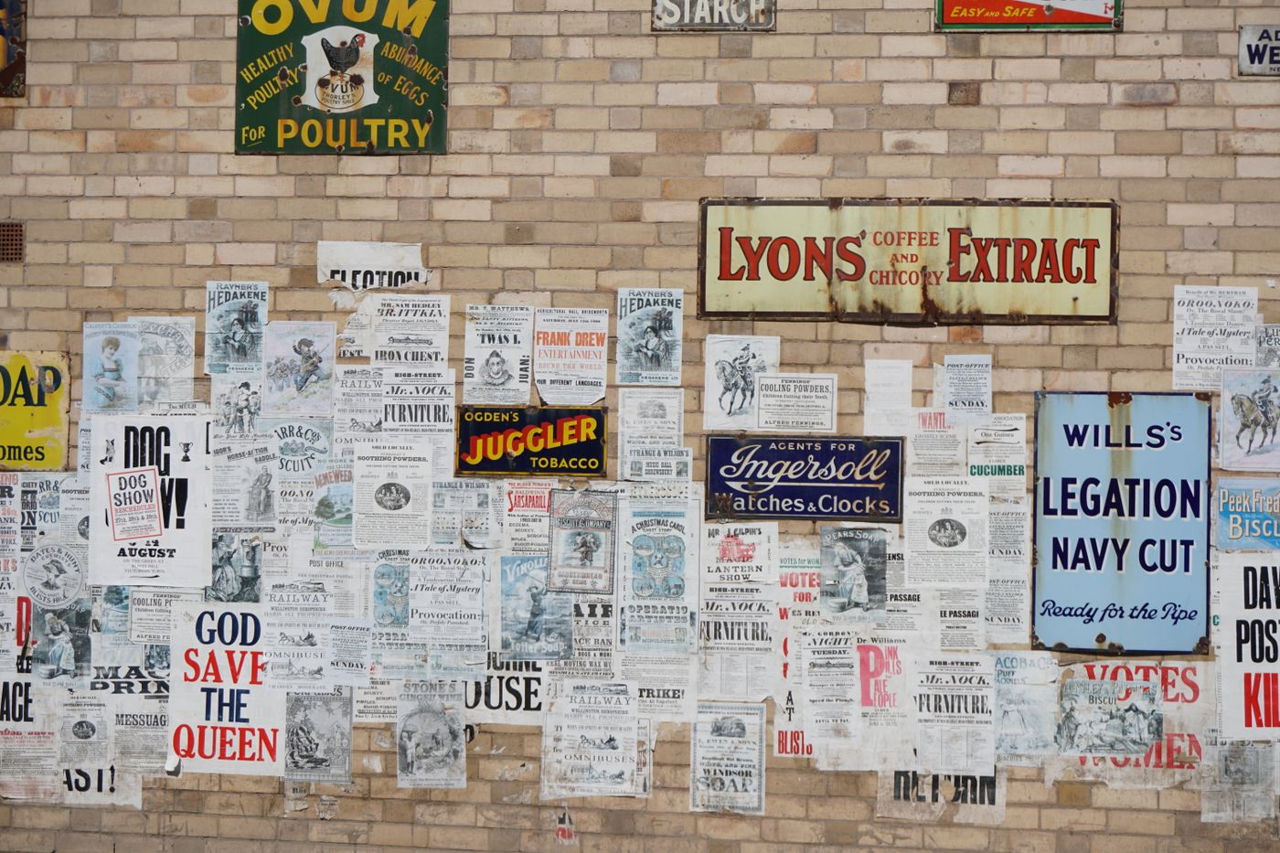 Vintage printed posters layered on a brick wall