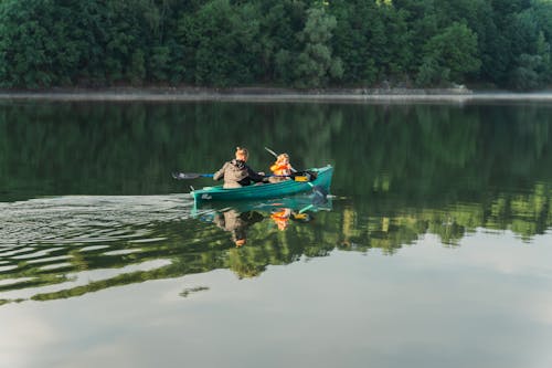 A Couple Paddling a Green Boat on Lake