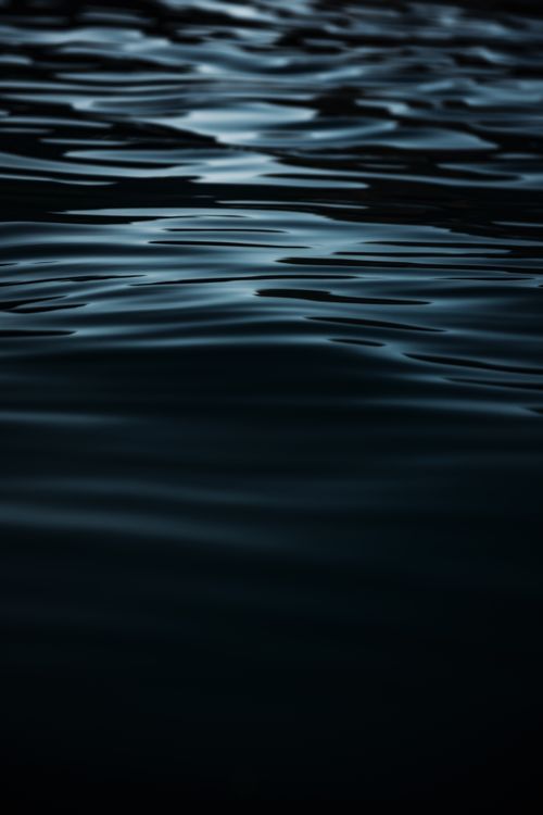 Free Serene dark water surface with gentle ripples and smooth texture, captured in a vertical shot. Stock Photo