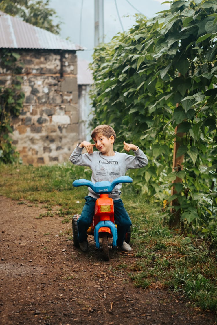 A Young Boy Riding A Motorcycle Toy Car