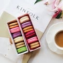 盒子里摆放着色彩缤纷的马卡龙，还配有咖啡和杂志，非常适合甜蜜的放纵