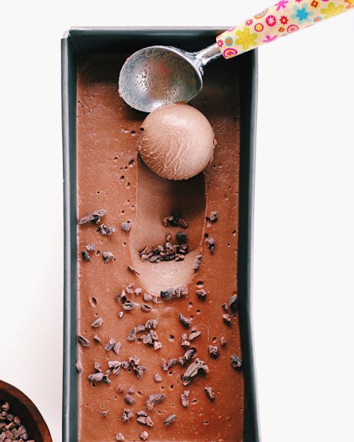 Шоколадное мороженое из ложки в черном контейнере
