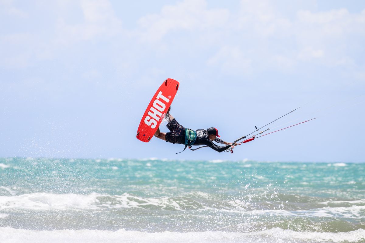 Toma de acción dinámica de kitesurf mientras un kitesurfista realiza trucos sobre e