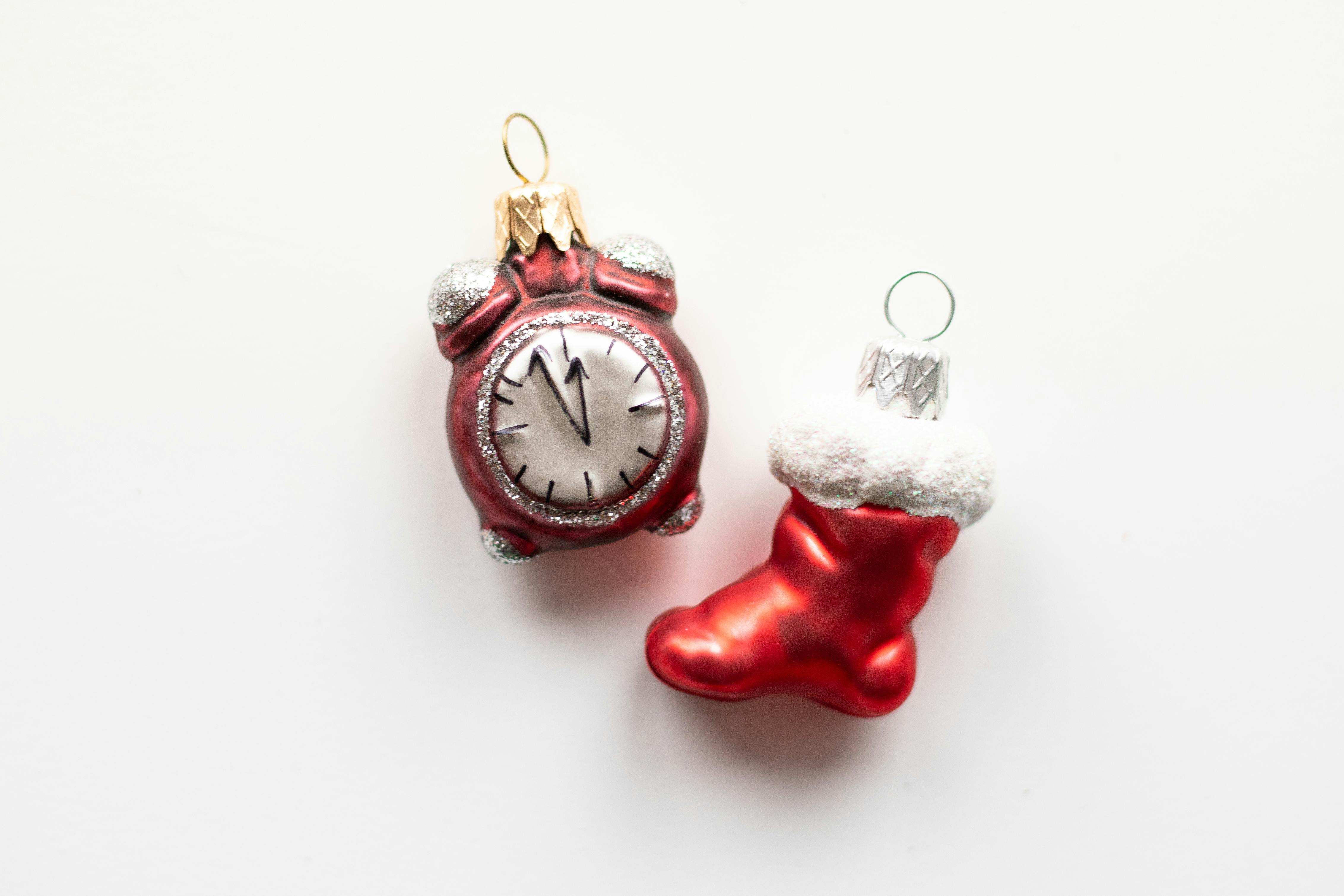 christmas stocking tags - Close-up of red Christmas ornaments, including a clock and stocking, on a white background.