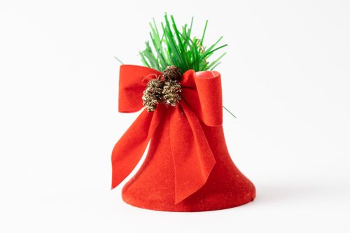 Free A close-up of a decorative red bell adorned with a vibrant bow, pine cones, and green foliage, perfect for Christmas. Stock Photo