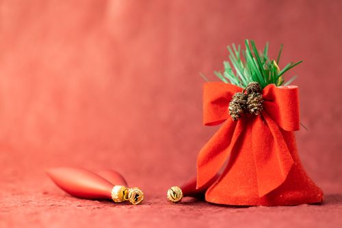 Free Close-up of red velvet bag with bow and ornaments on red background for holiday decor. Stock Photo