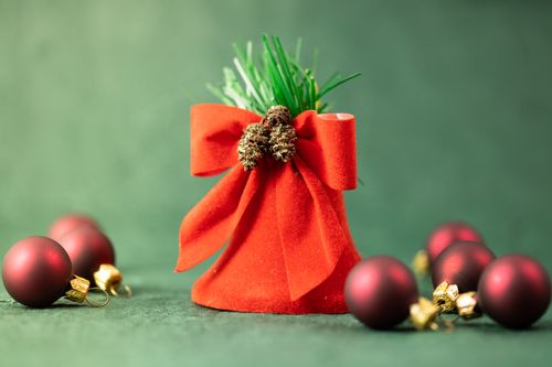 Free A vibrant display of red Christmas decorations with a velvet bow and ornaments on a green backdrop. Stock Photo