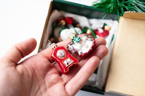 Free Close-up of a hand holding festive Christmas ornaments along with a box of decorations. Stock Photo