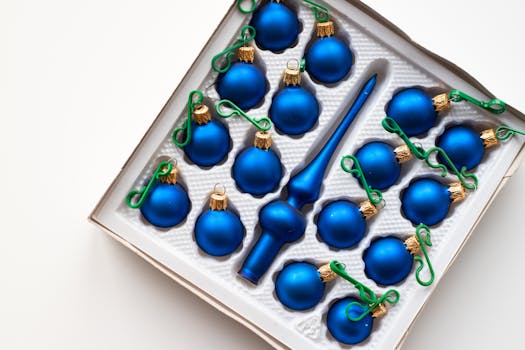 Set of blue Christmas ornaments with green hooks in a box, perfect for festive decor inspiration.