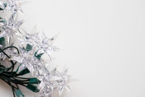 Free Elegant star-shaped Christmas lights with green wiring against a white background, offering ample copy space. Stock Photo