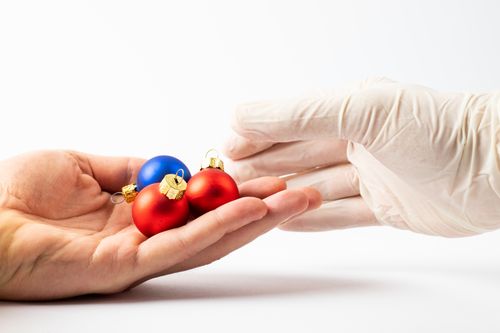 Free Close-up of Christmas ornaments being held by a gloved hand on a white background. Stock Photo