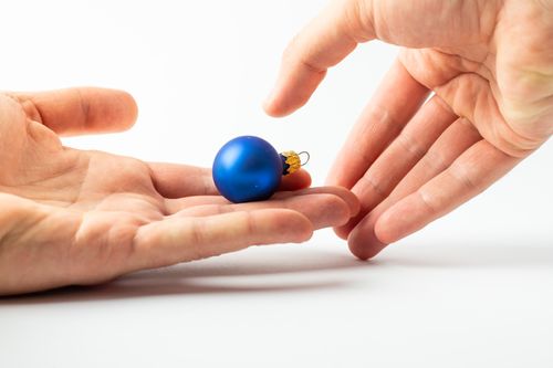 Free A delicate blue Christmas bauble cradled between hands on a white background. Stock Photo