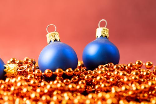 Free Elegant blue Christmas ornaments with gold beads on a red backdrop. Stock Photo