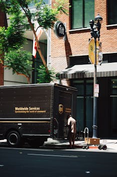UPS delivery courier loading packages into truck on urban street, showcasing transportation and logistics.